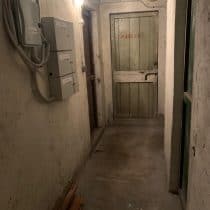 Scaricolo elettrico e porta in un seminterrato o cantina rustica.