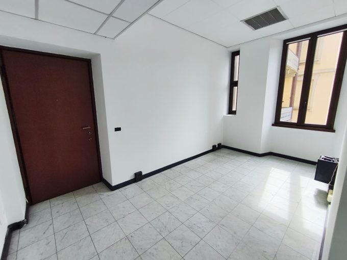 Vano ufficio vuoto con grandi finestre e pavimento in gres, ideale per uffici o studi professionali.