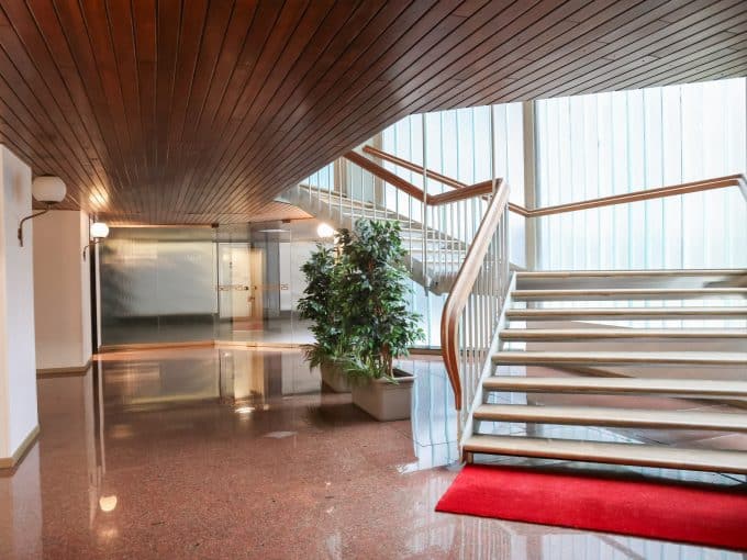 Ingresso spazioso con scale in legno e illuminazione naturale, ambiente elegante e accogliente.