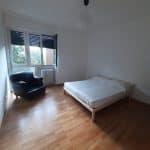 Ampia camera da letto arredata con letto e poltrona in soggiorno, luce naturale, pavimento in legno.