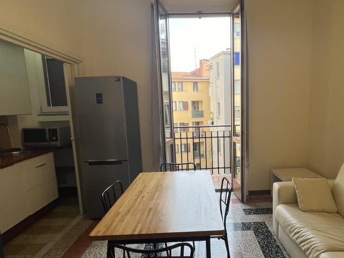 Ampia cucina soggiorno con balcone e luce naturale, arredato con stile moderno.