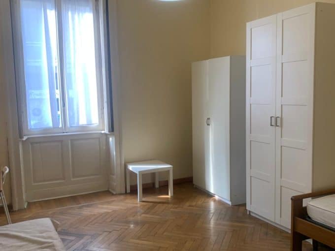 Ampio soggiorno con parquet in legno, grandi finestre e arredi bianchi, ideale per vivere in舒适e stile.