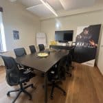 Prenotazione sala riunioni con tavolo e sedie ergonomiche in ufficio moderno.