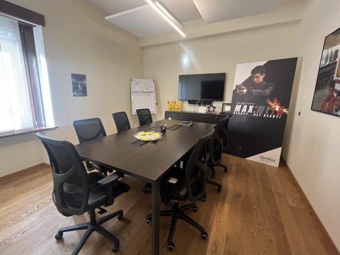 Prenotazione sala riunioni con tavolo e sedie ergonomiche in ufficio moderno.