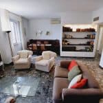 Luminoso soggiorno con divano, poltrone e libreria in ambiente elegante.