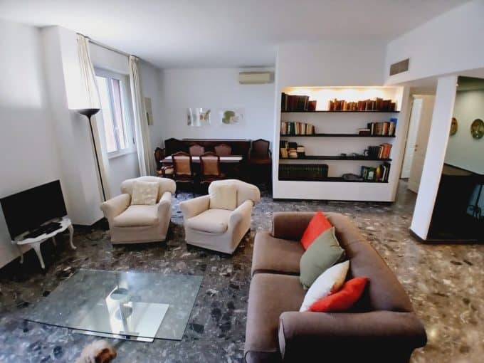 Luminoso soggiorno con divano, poltrone e libreria in ambiente elegante.