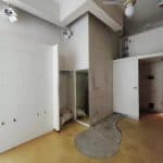 Vano interno in fase di ristrutturazione con pareti bianche e pavimento giallo. Spazi aperti e possibilità di personalizzazione.