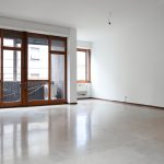 Ampio soggiorno con grandi finestre e balcone, luminoso e pronto per arredare.