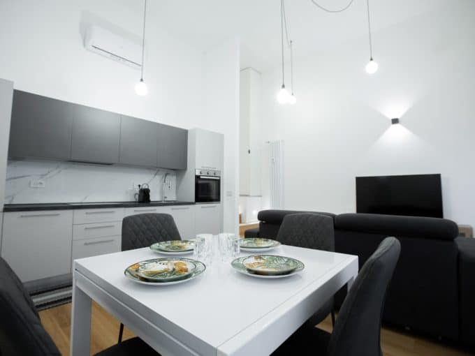 Appartamento moderno con soggiorno e cucina a vista, arredato con stile e illuminazione elegante.